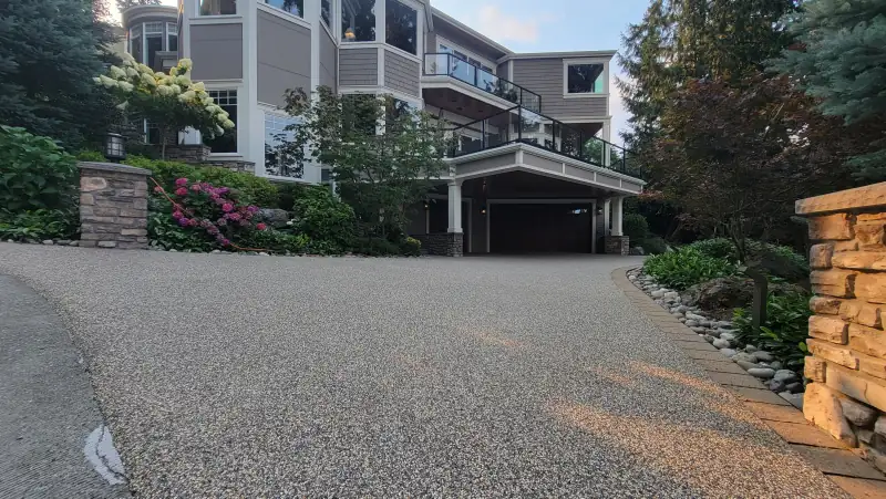 Big Sur blend driveway leading up to a multi-storey home with stone pillars